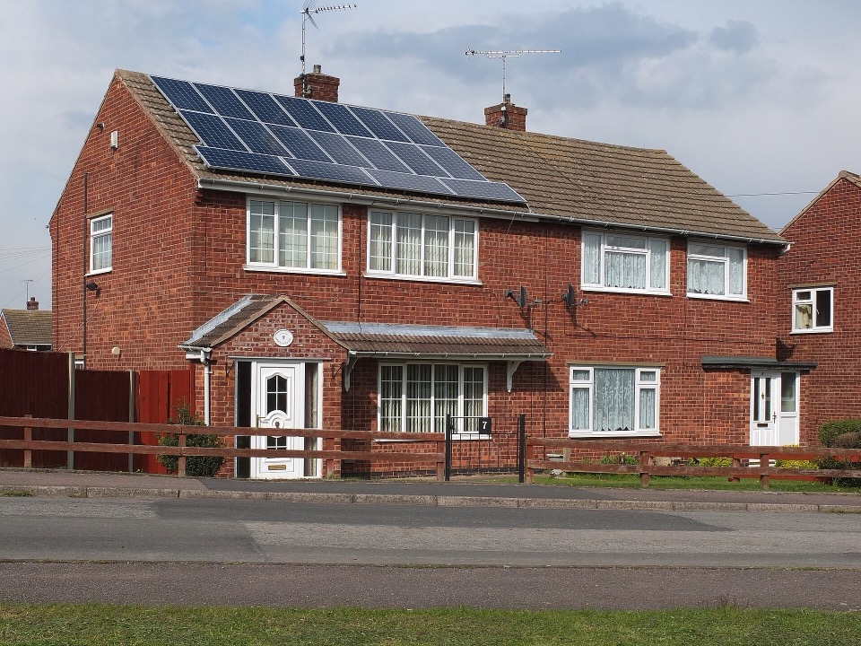Solar panels on the pitched roof of a red brick semi detached house in England