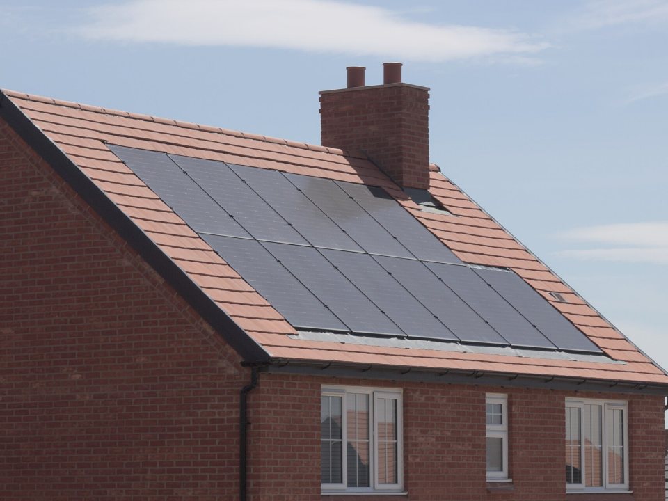 Solar panels covering the tiled roof of a brick house